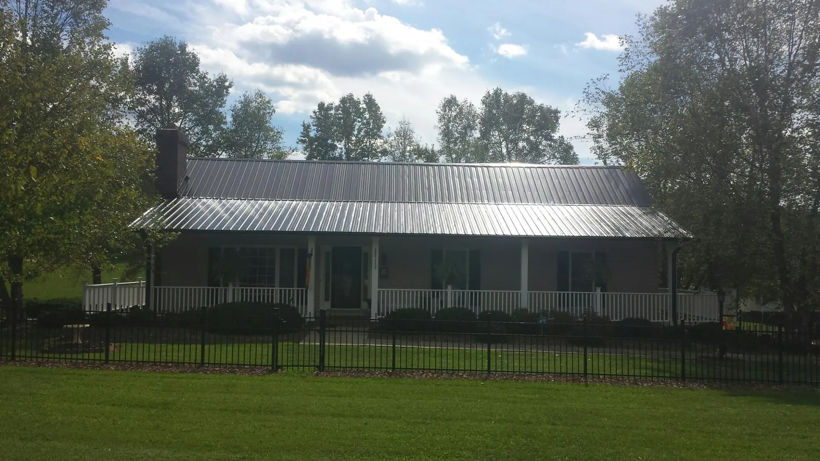 Gray metal roof on a brick ranch with a full width front porch — Gutter Guard Installation work by our crew in Pueblo