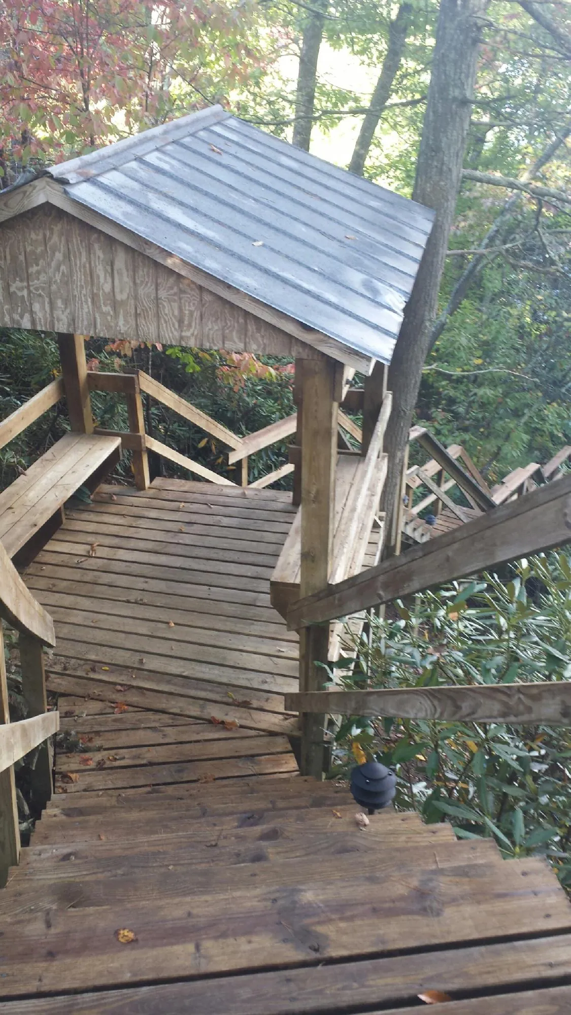 Metal roofed shelter over wooden steps on a wooded walkway — Skylight Repair & Installation work by our crew in Pueblo