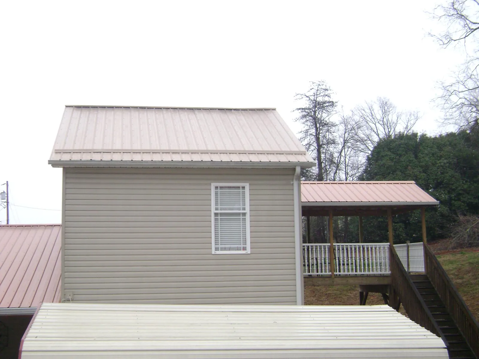 Tan metal roofs on a two story addition and attached porch, from a Roof Replacement job in Pueblo