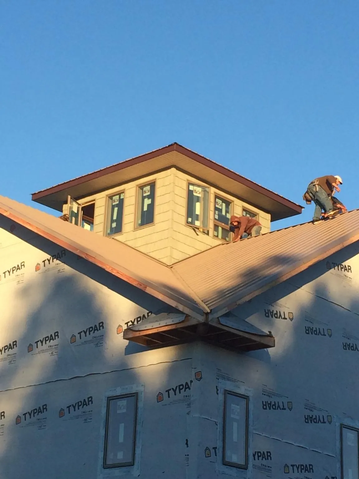 Roofers working around a rooftop cupola on a new metal roof at sunset — Roof Waterproofing in Pueblo by Roofing Brothers